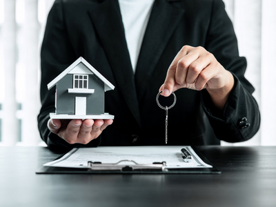person holding a toy house and a key
